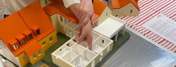 Et billede af en 3-model. der viser bygningen Døvblindehuset. To hænder - den ene ført - bevæger sig rundt i bygningen.